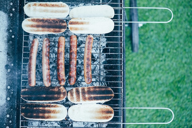 Vue de dessus de délicieux hot-dogs grillés sur un barbecue de qualité sur fond d'herbe verte