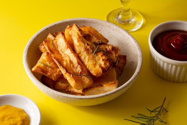 Vue de dessus Délicieux manioc frit dans un bol en céramique blanche fabriqué à la main sur fond de studio jaune