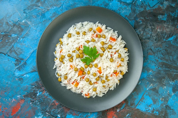 Vue de dessus d'un délicieux repas de riz avec carotte pisum servi avec du vert sur une plaque noire sur fond de couleur mélangée