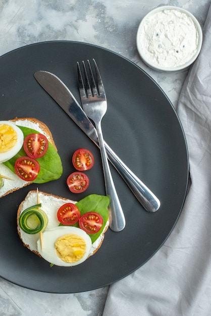 vue de dessus de délicieux sandwichs aux œufs avec couteau et fourchette à l'intérieur de la plaque fond blanc sandwich régime déjeuner toast alimentaire santé burger pain repas couleur