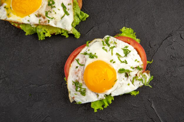 vue de dessus de délicieux sandwichs aux œufs avec des tomates sur fond sombre repas oeuf petit déjeuner nourriture omelette faire bouillir du pain déjeuner