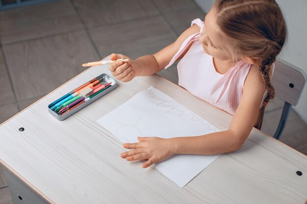 Vue de dessus d'un dessin d'un petit bel enfant en robe. Dessiner avec des crayons. Concept de passe-temps pour enfants. photo avec du bruit