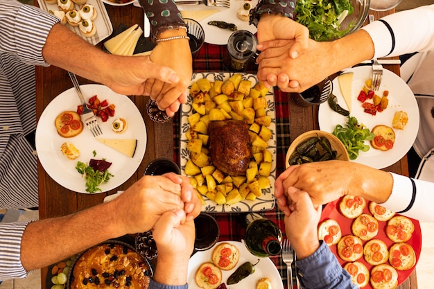 Vue de dessus et de dessus sur une grande table et des gens mangeant, priant et remerciant Dieu ou quelqu'un à propos de leur nourriture