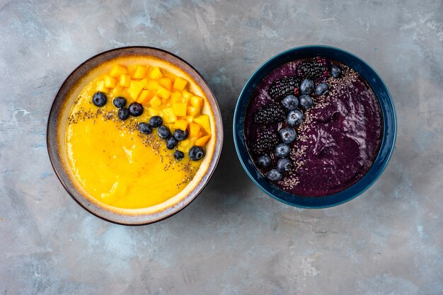 Vue de dessus de deux assiettes avec des smoothies jaunes et violettes