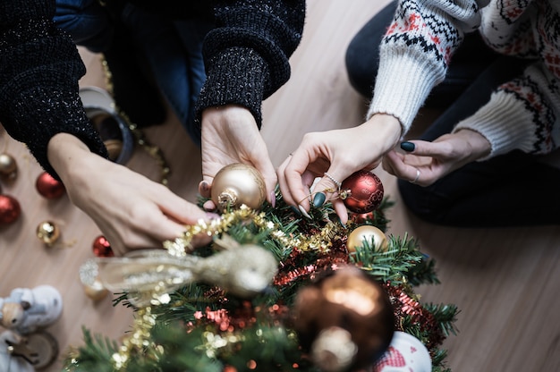 Vue de dessus de deux copines décorant l'arbre de vacances ensemble suspendus des boules de Noël rouges et dorées.