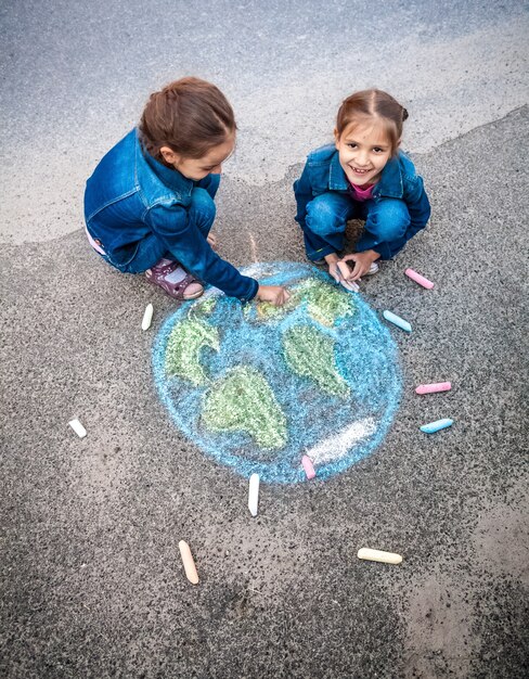 Vue de dessus de deux filles dessinant la Terre avec des craies