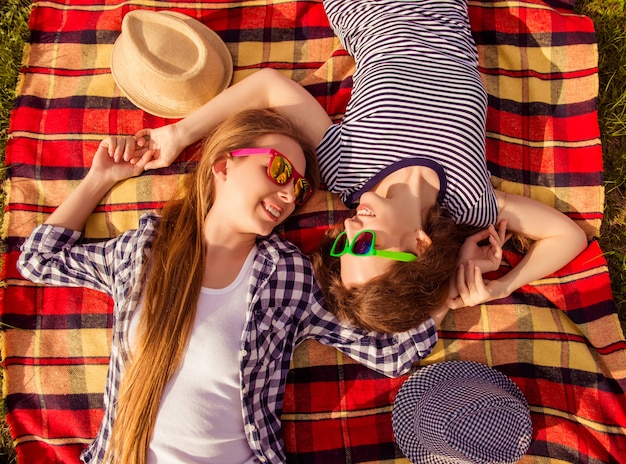 Vue de dessus de deux filles heureuses à lunettes allongé sur un plaid