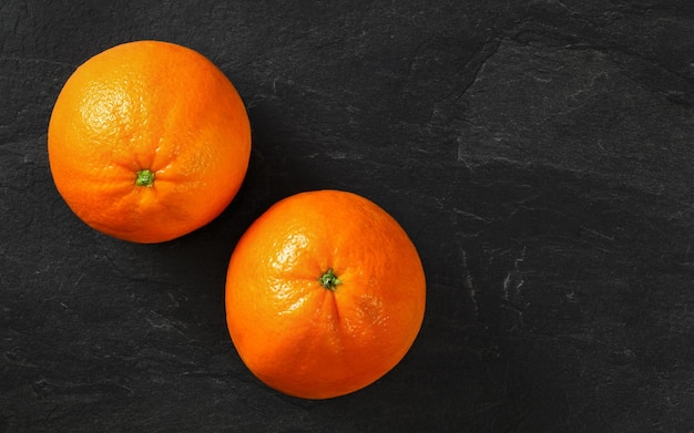 Vue de dessus - deux oranges sur ardoise noire, espace pour le texte à droite.