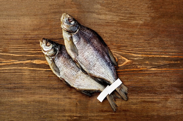 Vue de dessus de deux poissons de gardon salés salés avec des étiquettes sur les queues sur fond de bois rustique avec fond