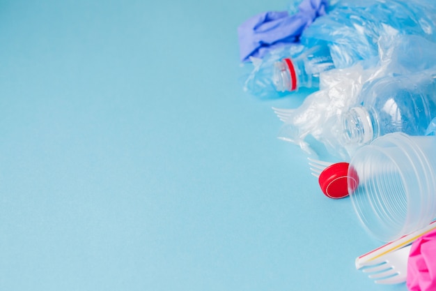 Vue de dessus de divers types de déchets plastiques jetables sur fond bleu