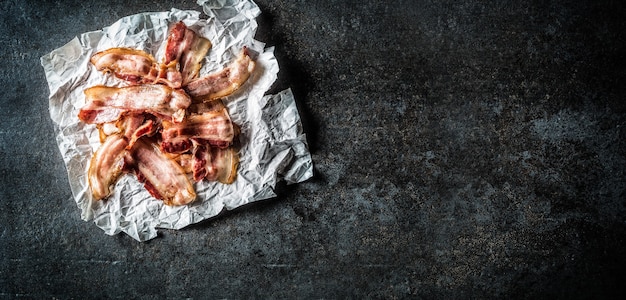 Vue de dessus du bacon rôti sur papier et planche de boucher.