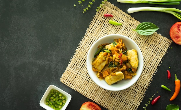 Vue de dessus du basilic sauté avec du poisson servi dans un bol sur fond de pierre sombre