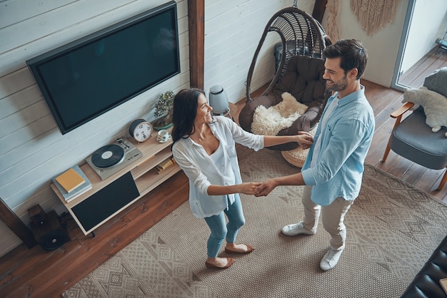 Vue de dessus du beau jeune couple souriant et dansant tout en passant du temps à la maison