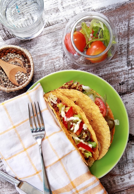 Vue de dessus du boeuf haché classique taco mexicain servi à la plaque verte avec table en bois à l'arrière-plan