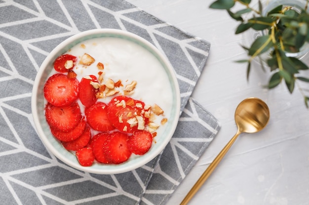 Vue de dessus du bol avec du yaourt à la noix de coco, des fraises et des amandes fraîches Le concept de petit-déjeuner et un mode de vie sain de style scandinave