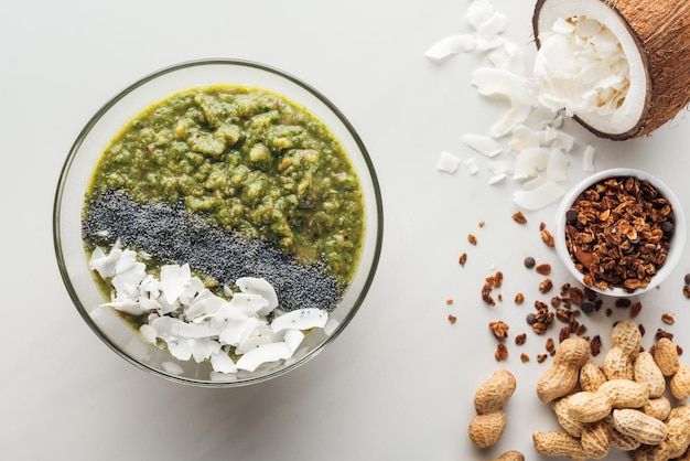 Vue de dessus du bol de smoothie vert frais avec des ingrédients sur fond blanc