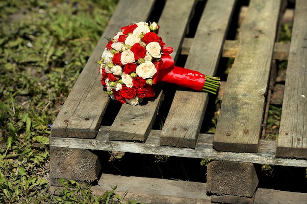 Vue de dessus du bouquet de luxe de fleurs rouges et blanches sur la palette vue de dessus avec un arc rouge le jour du mariage