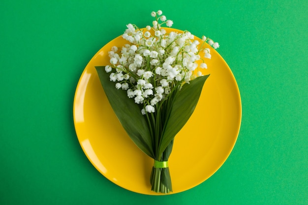 Vue de dessus du bouquet de muguet sur la plaque jaune