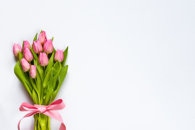 Vue de dessus du bouquet de tulipes roses, enveloppé de ruban rose sur fond blanc. Copiez l'espace.