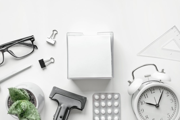 Vue de dessus du bureau avec Blank de bloc-notes Pen Clock et antidépresseurs sur fond blanc