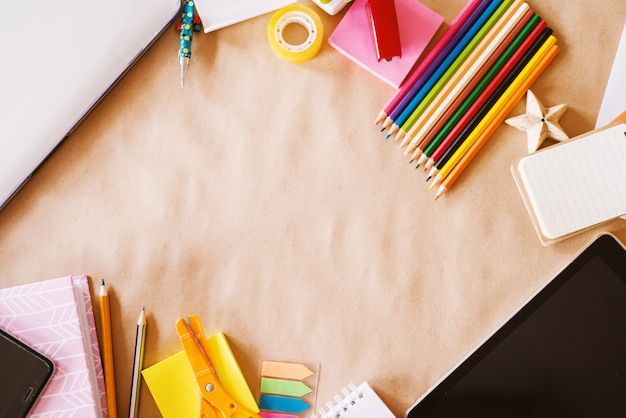 Vue de dessus du bureau de l'école pour enfants mis en place avec des crayons en bois pour l'art et les technologies modernes pour la navigation.