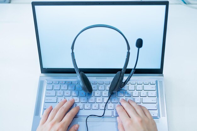 Vue de dessus du bureau de l'opérateur du centre d'appels Gros plan sur des mains féminines tapant sur un ordinateur portable Une femme méconnaissable travaille dans les services d'assistance Casque sur le clavier