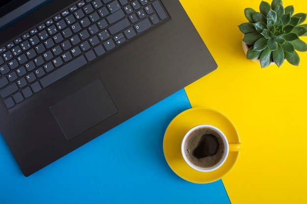 Vue de dessus du bureau avec ordinateur portable, tasse à café et cactus. Mise à plat du bureau de l'espace de travail.