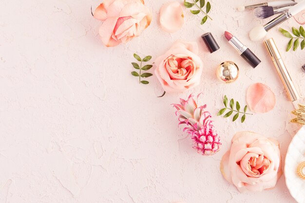 Vue de dessus du bureau de travail de femme beauté blogger avec décoratif cosmétique, des feuilles et des feuilles de palmier, plaque de feuille, enveloppe sur une table pastel rose