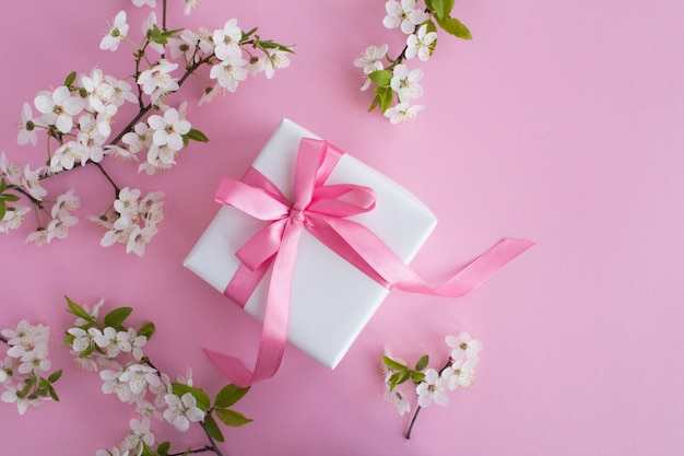 Vue de dessus du cadeau et des branches d'arbres en fleurs sur la surface rose