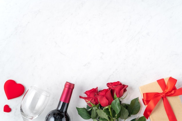 Vue de dessus du cadeau de la Saint-Valentin avec rose et vin, concept de design festif pour un repas de rencontres spécial vacances.