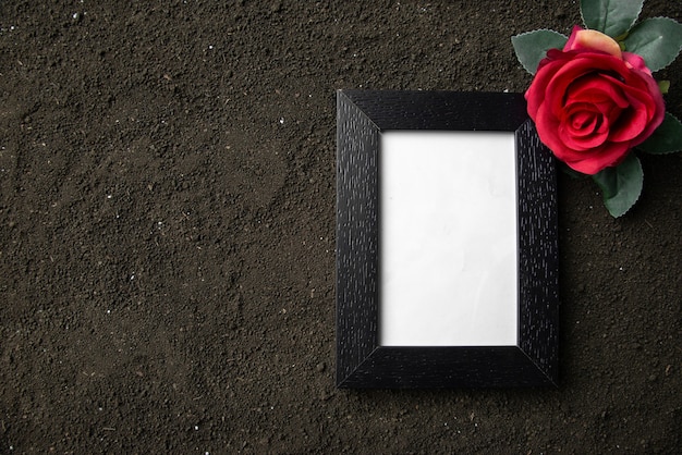 Vue de dessus du cadre photo vide avec une fleur rouge sur un sol sombre