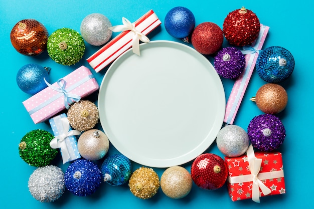 Vue de dessus du cadre de vacances sur coloré, assiette, cadeaux, boules et décorations de Noël, concept de dîner de nouvel an