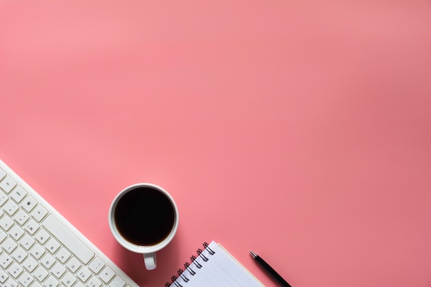 Vue de dessus du café avec un cahier et autres fournitures sur fond rose et fond