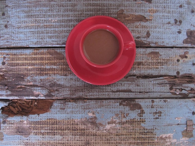 Vue de dessus du café chaud dans une tasse rouge sur une vieille table en bois