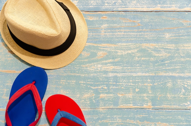 Vue de dessus du chapeau de paille et des tongs sur une table en bois bleu clair. Concept de vacances de plage d'été avec espace copie.