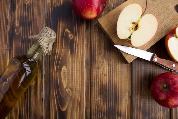 Vue de dessus du cidre de vinaigre de pomme dans la bouteille en verre sur la surface en bois