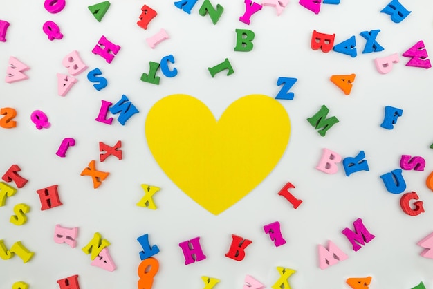 Vue de dessus du coeur jaune et des lettres anglaises colorées Le concept de cours d'étude de retour à l'école Amour pour aller à l'école