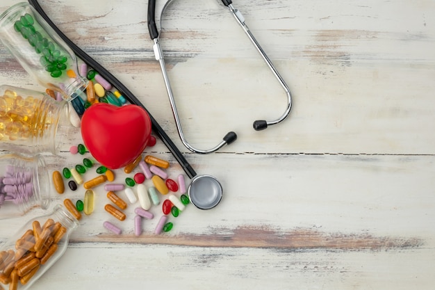 Vue de dessus du coeur rouge et de la médecine sur le plancher en bois