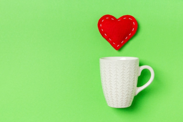 Vue de dessus du coeur textile rouge éclaboussant dans une tasse