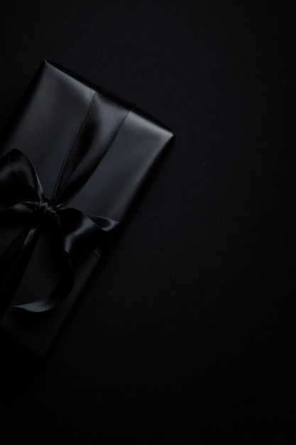 Vue de dessus du coffret cadeau noir avec des rubans noirs isolés sur fond noir