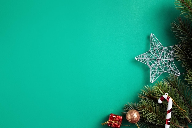 Vue de dessus du concept de design de fond de Noël avec une branche de sapin et des décorations sur fond de table verte.