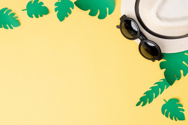 Vue de dessus du concept de l&#39;été avec des lunettes de soleil et un chapeau sur fond jaune