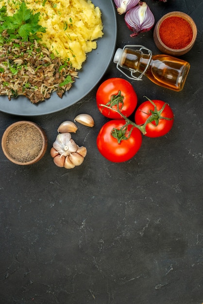 Vue de dessus du délicieux dîner tombé bouteille d'huile poivron rouge aliments frais sur fond noir