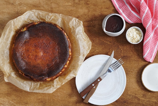 Vue de dessus du délicieux gâteau au fromage basque brûlé servi avec de la confiture de chocolat et une serviette rose sur la vue de dessus de table rustique