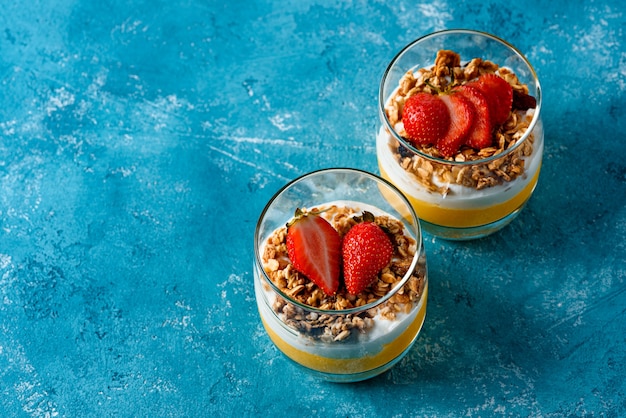 Vue de dessus du dessert à la mangue, granola, ricotta décorée de fraises