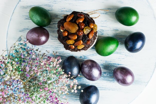 Vue De Dessus Du Fond En Bois Bleu Avec Gâteau De Pâques, œufs Colorés Et Fleurs Printanières.