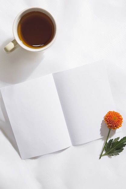 Vue de dessus du fond de tissu voile avec une tasse de thé, une fleur d'oranger et un morceau de papier blanc avec un espace pour le texte