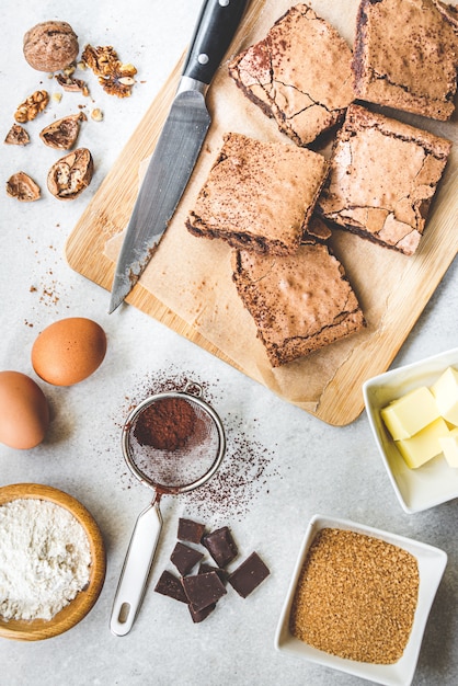 Vue de dessus du gâteau au brownie fait maison fraîchement préparé avec des ingrédients de la recette sur blanc rustique.