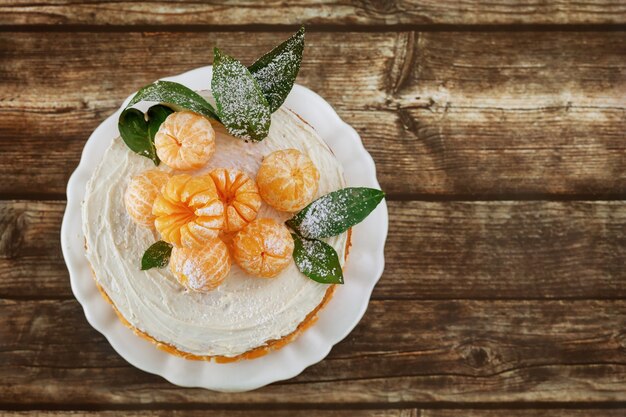 Vue De Dessus Du Gâteau Nu De Mandarines Avec Des Feuilles Sur Fond Rustique.