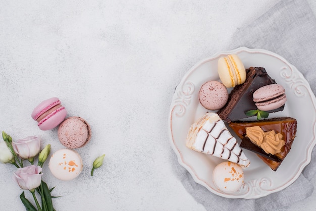 Vue de dessus du gâteau sur la plaque avec des macarons et rose